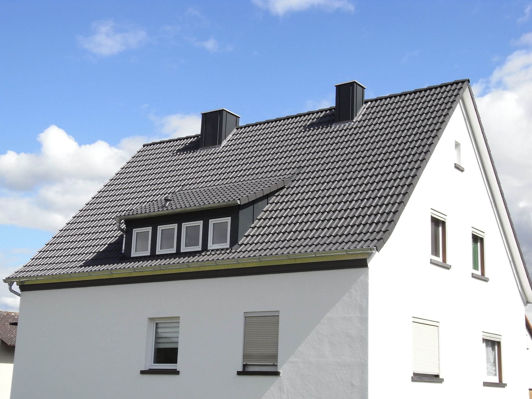 Fertig eingedecktes Dach mit Gaube und Kaminverkleidung